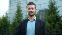 Ambitious young man is showing thumbs-up hand gesture standing outdoors with business center in background. Successful people and entrepreneurship concept. — Photo Vitaly Gariev / Unsplash