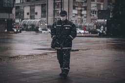 man in black coat standing on sidewalk during daytime — Photo Aleksandar Velickovic / Unsplash