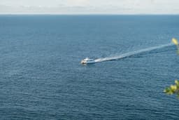 a small boat traveling across a large body of water — Photo Rodrigo Rodrigues | WOLF Λ R T / Unsplash