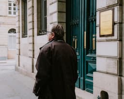 a man walking down a street next to a tall building — Photo Mathias Reding / Unsplash