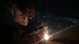 a man welding a piece of metal in the dark — Photo Surya Prakash / Unsplash