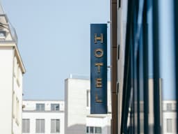 a hotel sign hanging off the side of a building — Photo Loner Deer / Unsplash