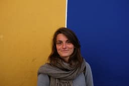 a woman standing in front of a blue and yellow wall — Photo Hugo Cornuel / Unsplash