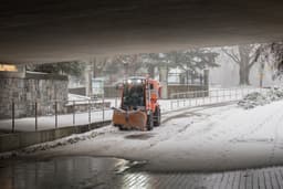 An Orange Snowplow moving snow and dropping salt. — Photo Albert Stoynov / Unsplash