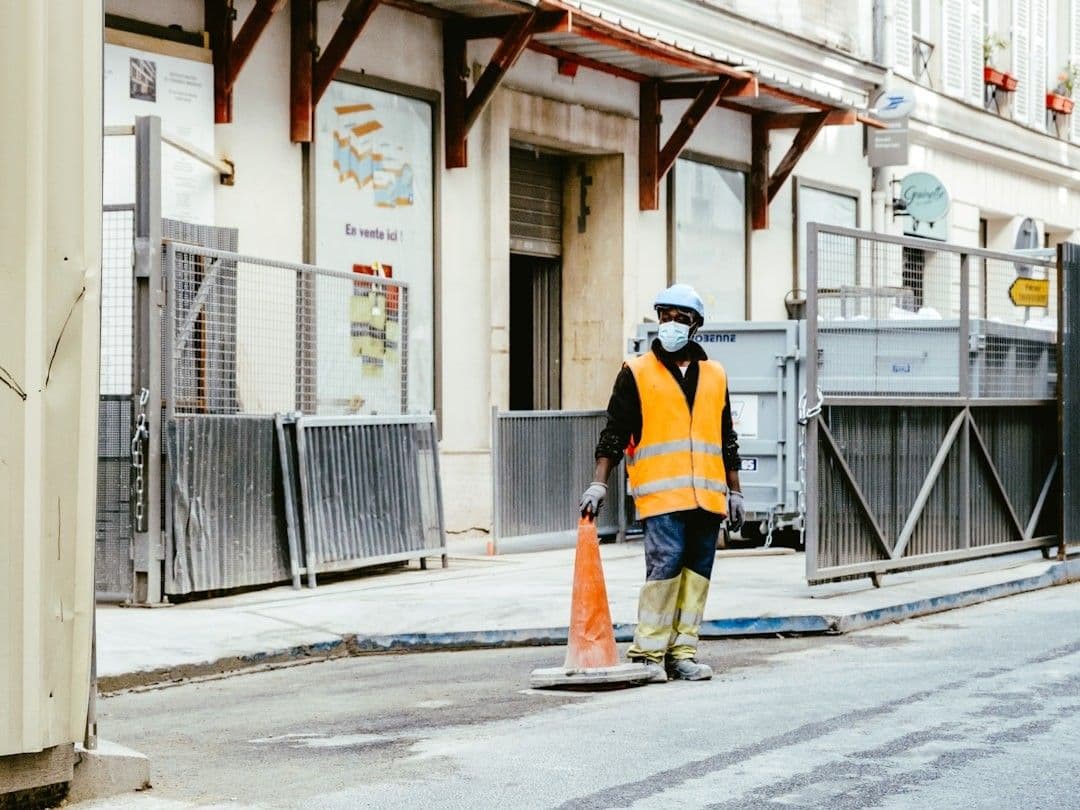 man in orange and black jacket walking on sidewalk during daytime — Photo Mathias Reding / Unsplash
