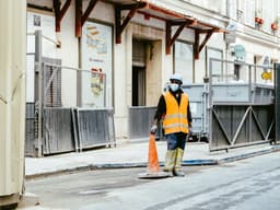 man in orange and black jacket walking on sidewalk during daytime — Photo Mathias Reding / Unsplash