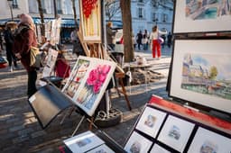 A woman standing next to an easel with paintings on it — Photo Sung Jin Cho / Unsplash