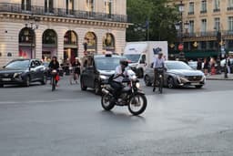 A man riding a motorcycle down a street next to tall buildings — Photo Ethan / Unsplash