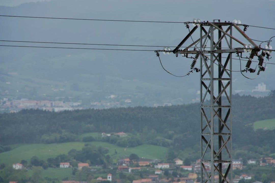 a view of a power line with a city in the background — Photo Pablo Sanchez Cuesta / Unsplash