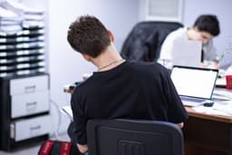 a man sitting at a desk in front of a laptop computer — Photo Anton Savinov / Unsplash