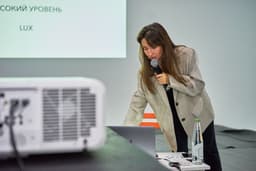 A woman holding a microphone in front of a projector screen — Photo Valery Tenevoy / Unsplash