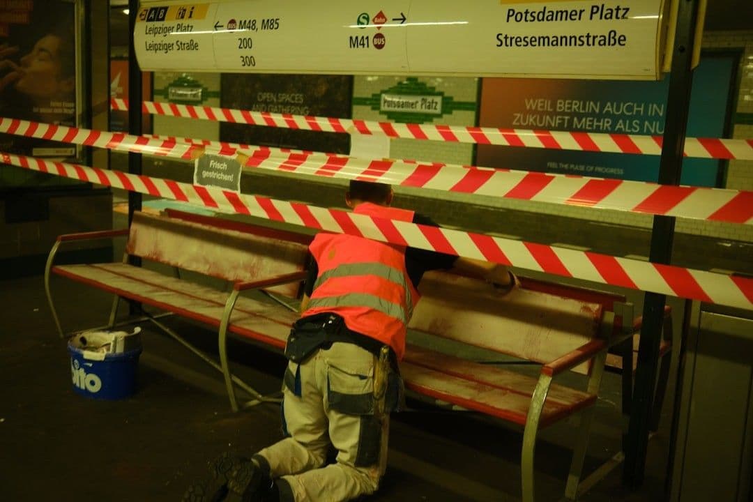 a man in an orange safety vest working on a bench — Photo Alan Alves / Unsplash