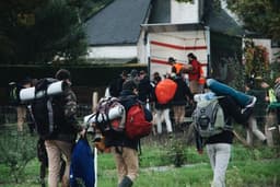 men carrying bags walking near house — Photo Maël BALLAND / Unsplash