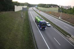 a green and blue truck driving down a highway — Photo Maciej Kaliszewski / Unsplash