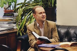 man holding book while sitting on black leather couch — Photo Alizea Sidorov / Unsplash