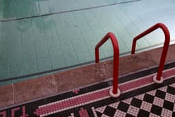 Red ladder leads into a swimming pool — Photo Ryan Waldman / Unsplash