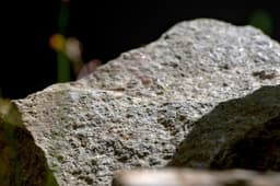 Here's a caption for the image: rough granite rock, illuminated by light. — Photo Naufan Rusyda Faikar / Unsplash