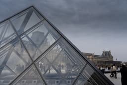 a pyramid shaped building with people walking around it — Photo aronskaya / Unsplash