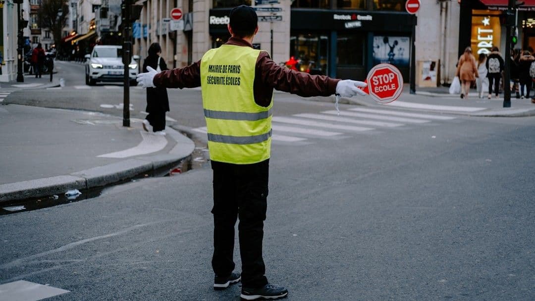 a man in a safety vest holding a stop sign — Photo Mathias Reding / Unsplash