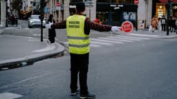 a man in a safety vest holding a stop sign — Photo Mathias Reding / Unsplash