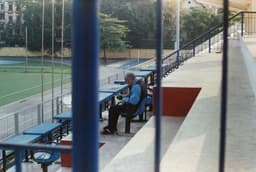 a man sitting on a bench at a baseball field — Photo Nguyễn Hiệp / Unsplash