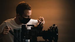 a man wearing a face mask and holding a camera — Photo Billy Freeman / Unsplash