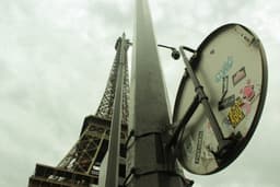 a street sign with stickers on it in front of the eiffel tower — Photo Lucas Medeiros / Unsplash