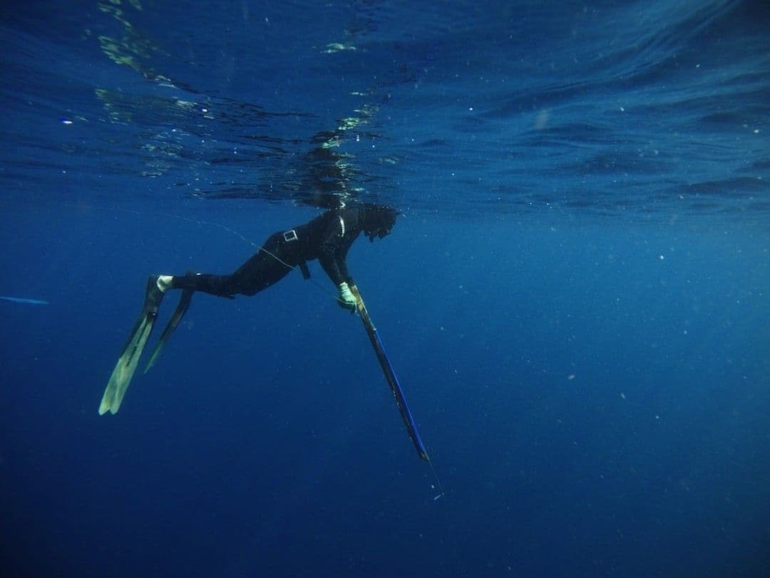 a person in a wet suit is in the water — Photo Her Pratam / Unsplash