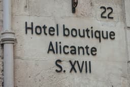 A sign on the side of a building that says hotel boutique alicante s — Photo Sol Ponce / Unsplash