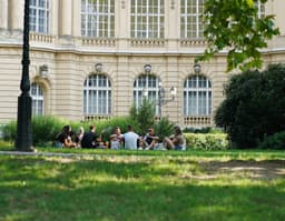 people sitting on green grass field near white concrete building during daytime — Photo Paréj Richárd / Unsplash