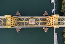 Aerial view of a yellow drawbridge over dark water. — Photo Leo_Visions / Unsplash