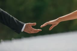 A bride and groom reaching their hands out to hold each other — Photo Lucas T / Unsplash