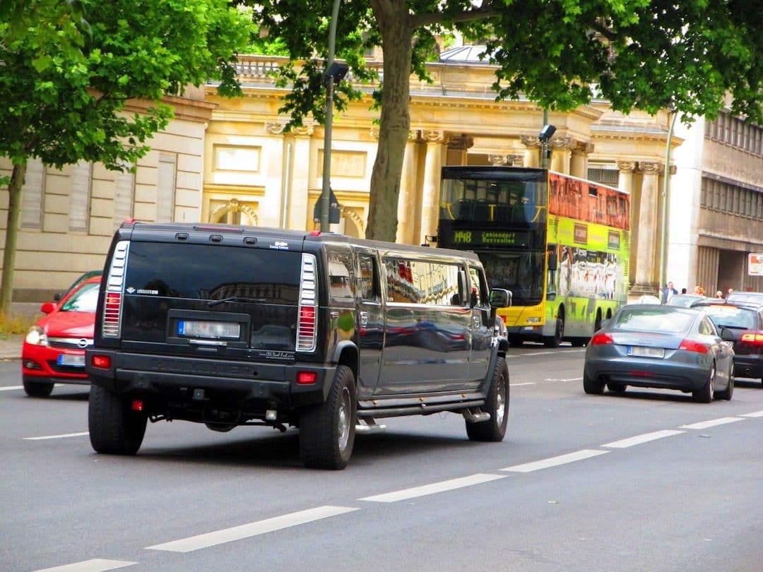 A black truck driving down a street next to tall buildings — Photo Suraj Tomer / Unsplash