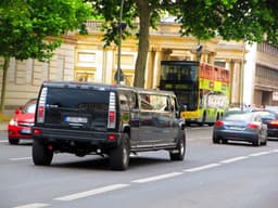 A black truck driving down a street next to tall buildings — Photo Suraj Tomer / Unsplash