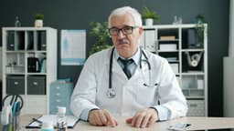 Portrait of joyful doctor senior man in uniform talking waving hand showing bottles with pills in hospital office during online call with patient. Medicine, people and consultation concept. — Photo Vitaly Gariev / Unsplash