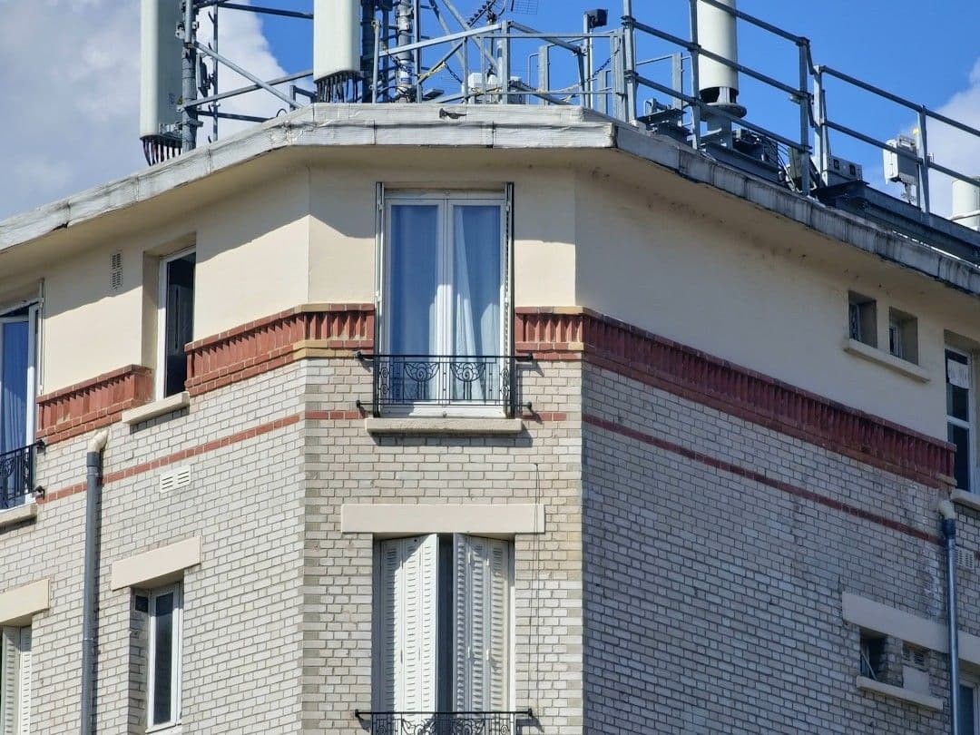 a tall brick building with a metal balcony — Photo Fordeuf Blvd / Unsplash