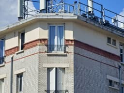 a tall brick building with a metal balcony — Photo Fordeuf Blvd / Unsplash