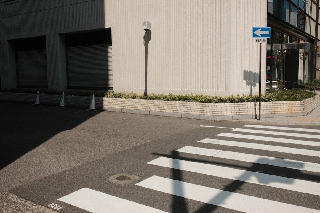 Crosswalk and building corner with directional sign — Photo MAK / Unsplash