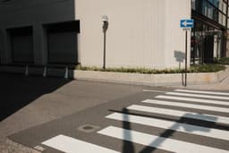 Crosswalk and building corner with directional sign — Photo MAK / Unsplash