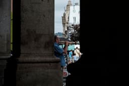 a man holding an umbrella standing next to a tall building — Photo Samuel Jerónimo / Unsplash