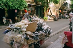 A man pushing a cart full of items down a street — Photo Khanh Do / Unsplash